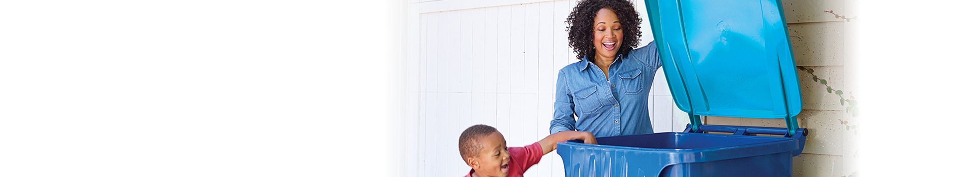 An image of a woman and a child placing an item inside a recycling cart