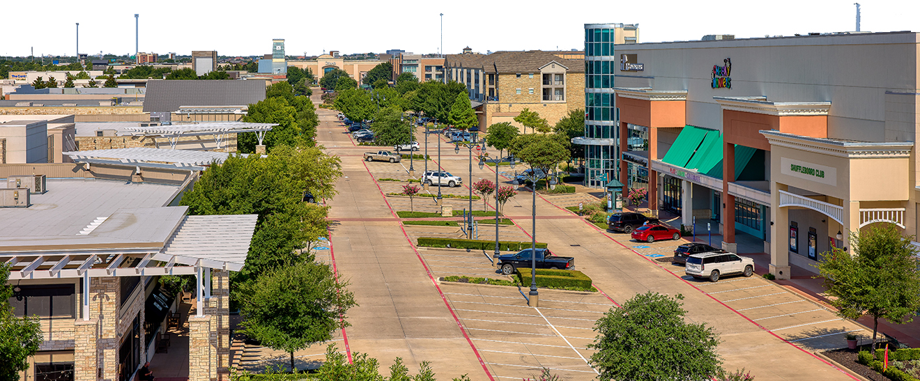 An image of a street and parking area in the middle of an outdoor shopping mall
