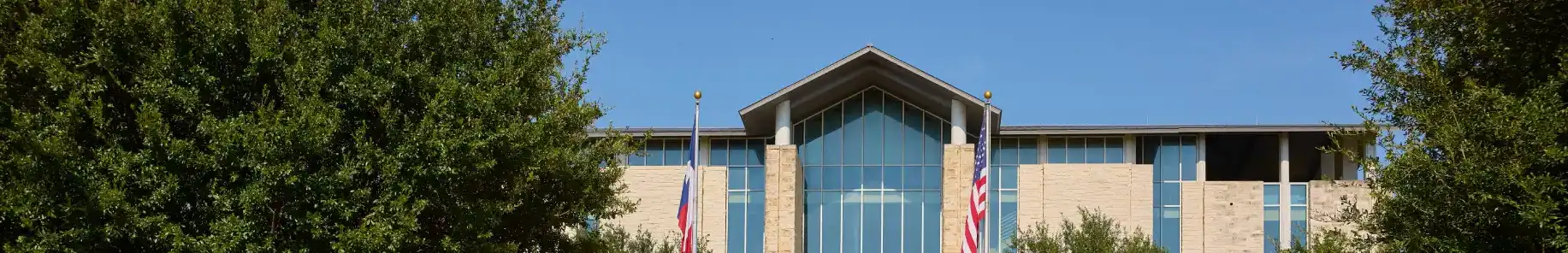 An image of the exterior of Fairview Town Hall with a U.S. flag and a Texas flag in the foreground