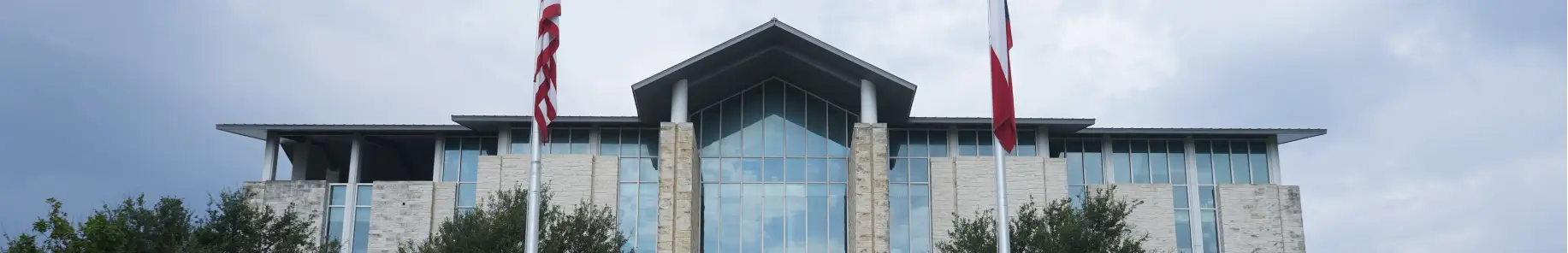An image of the exterior of Fairview Town Hall with a U.S. flag and a Texas flag in the foreground