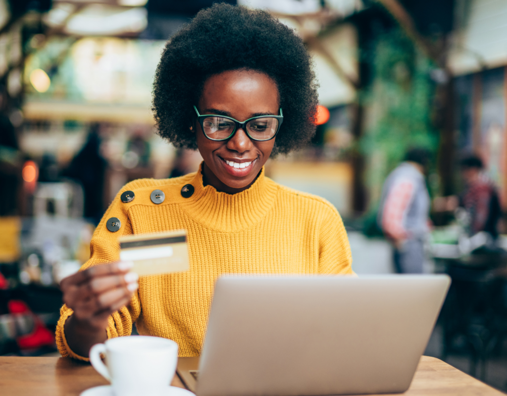 Image of woman holding credit card while sitting in front of a laptop computer