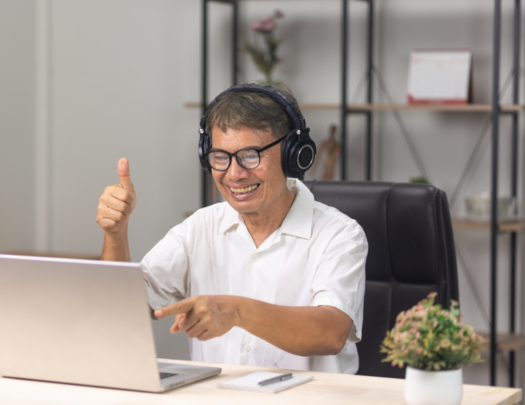 Image of a man using a laptop computer and smiling while giving a thumbs up